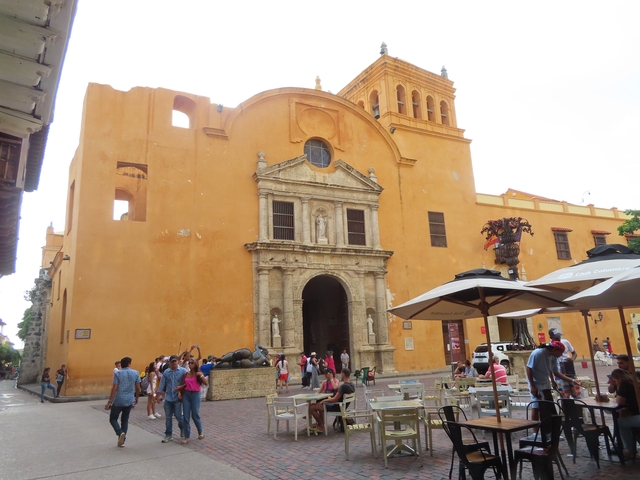       A historic yellow building with people gathered around.
  