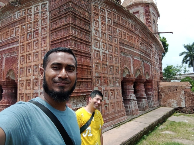 Two people in front of a historical terracotta temple.
