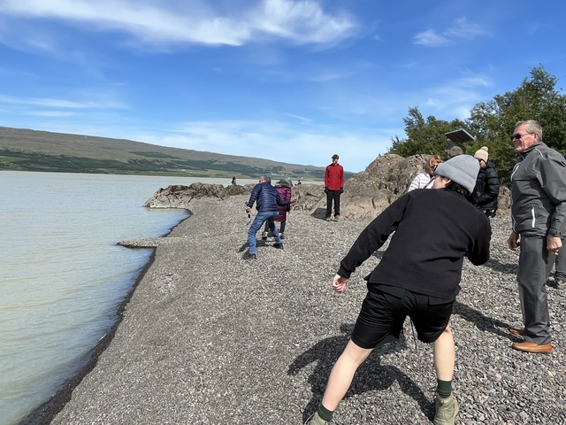       Group of people skipping stones by a lake.
  