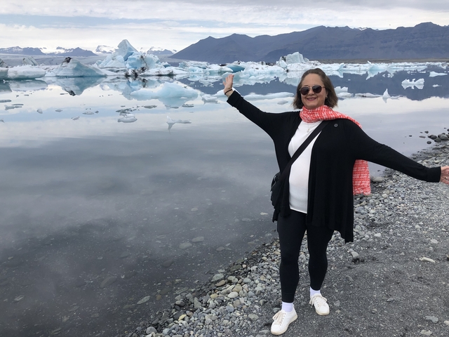       Woman posing by an icy lake with glaciers.
  