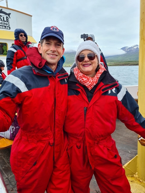       Two people in red jackets in a boat setting.
  