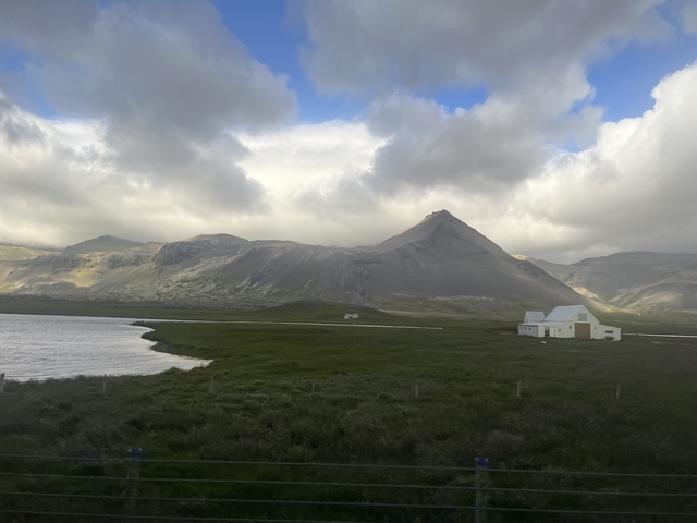       House in a vast landscape with mountains and a lake.
  