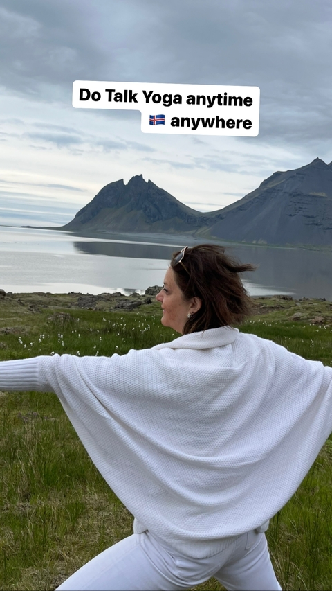       Woman standing with arms outstretched in front of a scenic landscape.
  