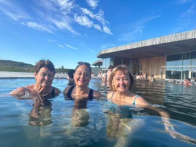       Three women in a geothermal pool with modern architecture.
  