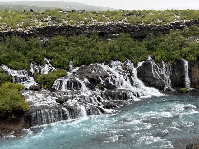       Layered waterfalls flowing into a turquoise river.
  