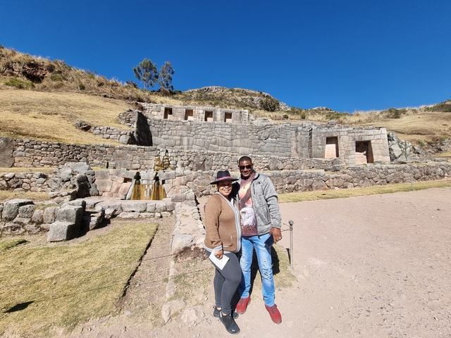 Two people standing in front of ancient ruins.