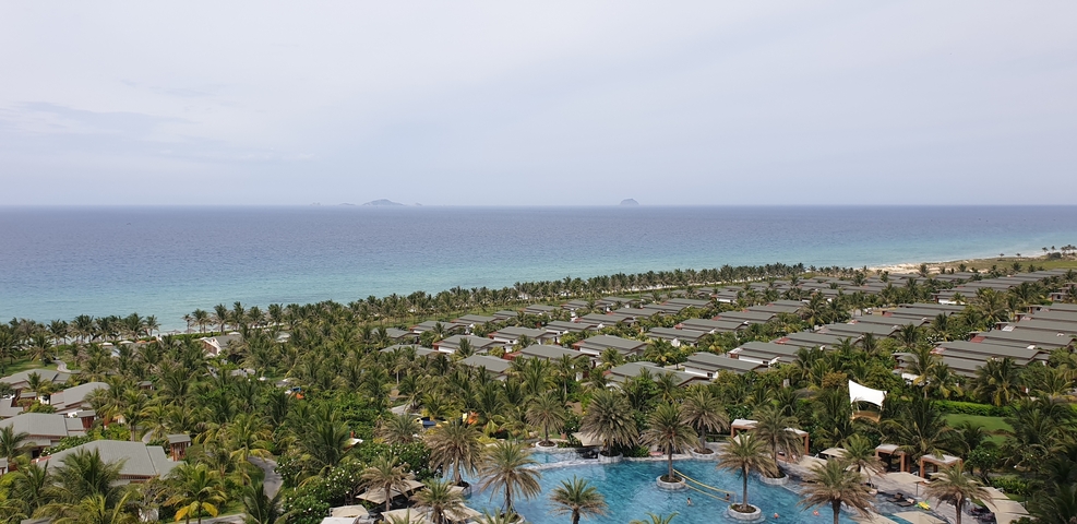       Resort area with palm trees, clear water, and distant islands.
  