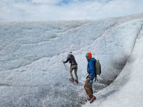 Two people climbing on a glacier.