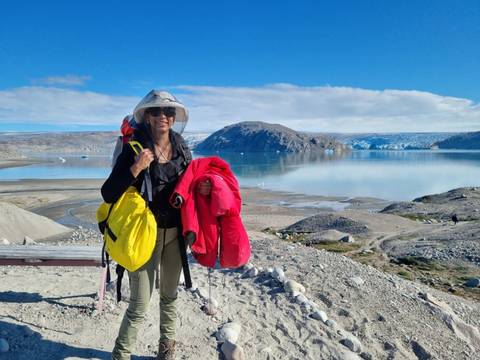       Hiker with gear posing with icy lake and landscape in background.
  