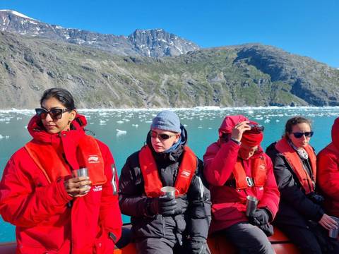 People in red jackets on a boat with icy landscape.