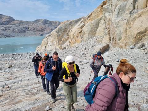 Group hiking on rocky terrain beside a lake.