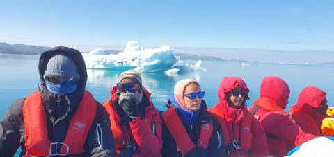 Group of people in a boat near icebergs.
