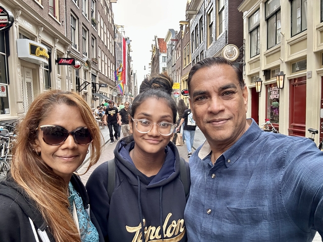 Family on a street with shops and people.