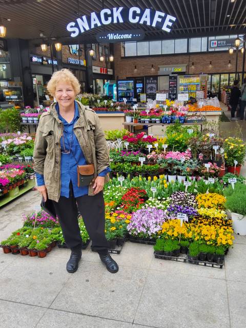 Woman standing in front of a colorful flower stall.