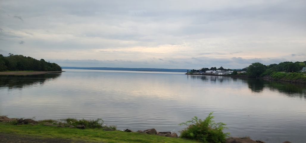 Calm waters with buildings in the far background under a cloudy sky.