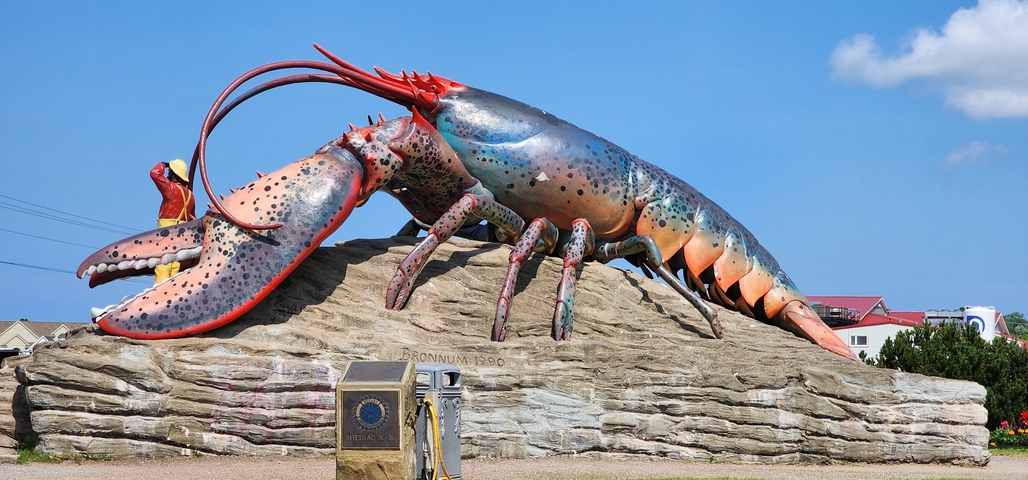Giant colorful lobster statue on a rock base.