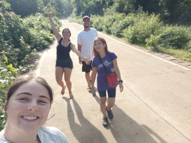 Group selfie on a road surrounded by greenery.