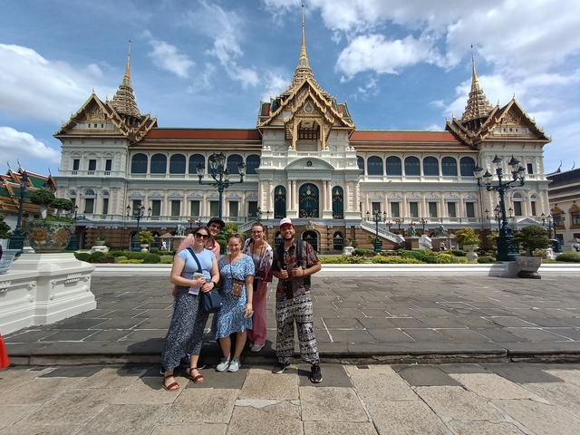       Group posing in front of a grand palace with intricate architecture.
  