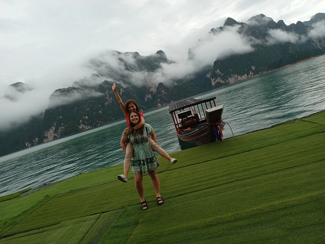 Two people having fun near a scenic water body with mountains in the background.