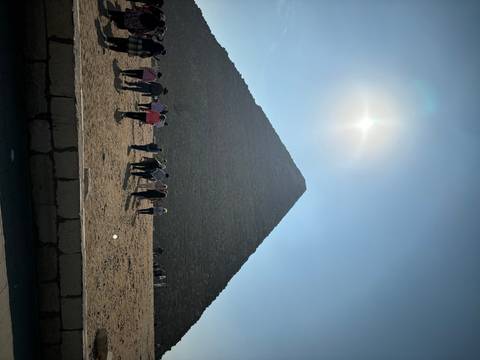       Tourists approaching a pyramid in the desert.
  
