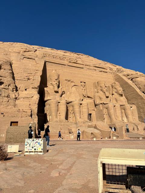       Colossal statues at the entrance of Abu Simbel with tourists.
  