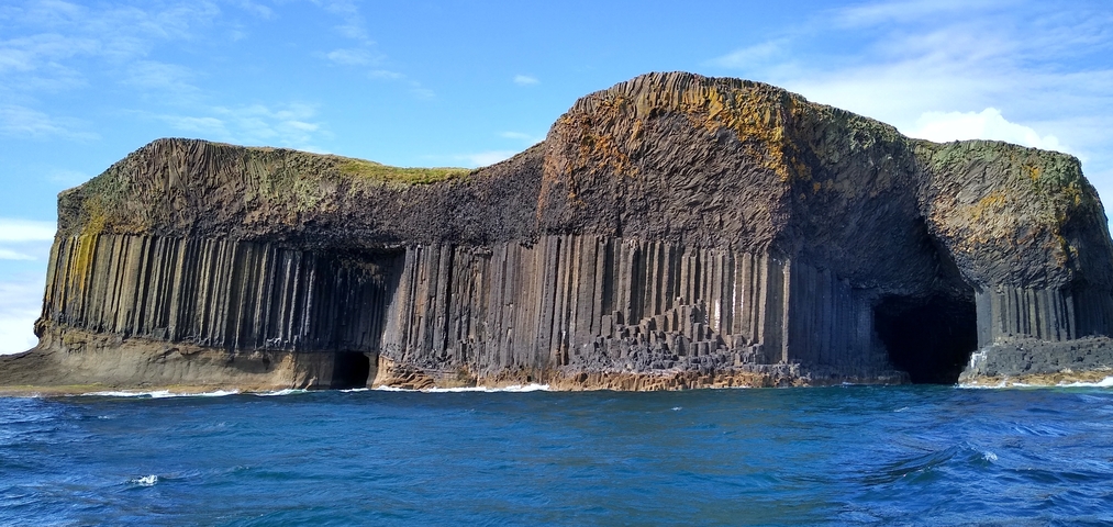 Dramatic basalt columns and caves on the shore.
