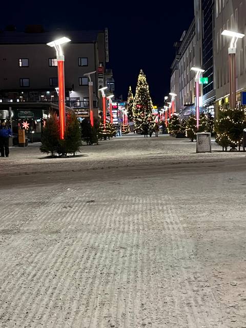 Snowy street with festive decorations and lights.