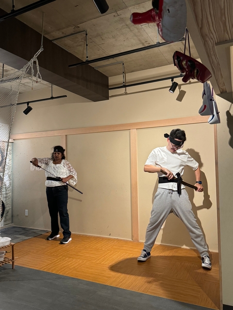 Two people practicing martial arts with swords indoors.