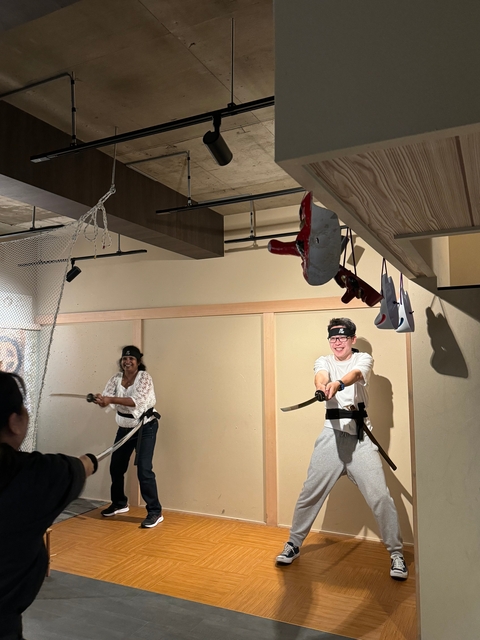 Two people practicing martial arts with swords indoors.