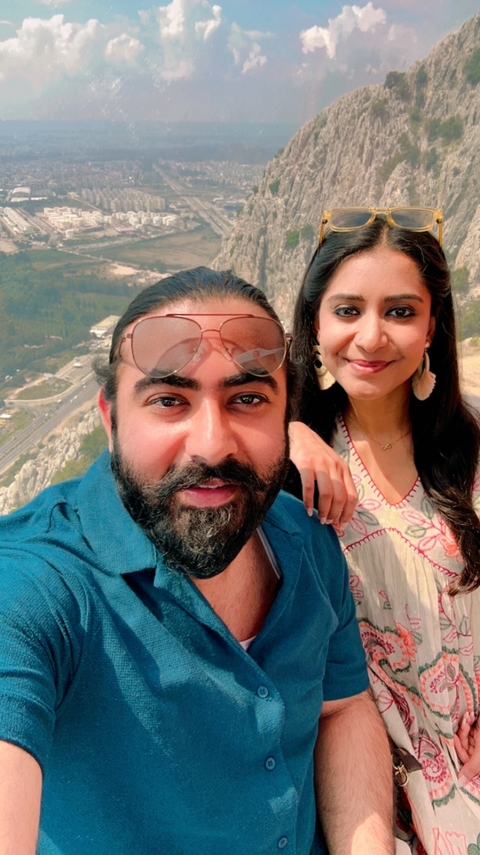 Smiling couple taking a selfie with a scenic backdrop.