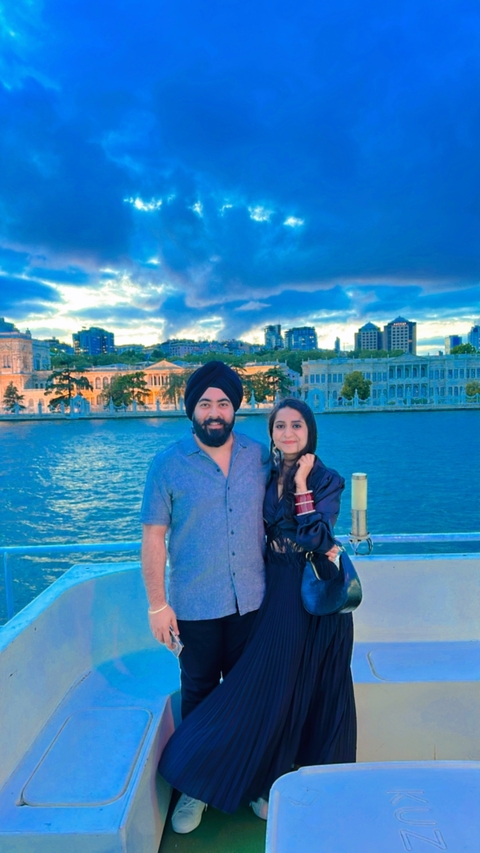       Couple on a boat with a cityscape in the background.
  