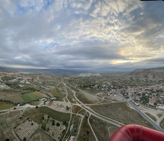 Panoramic view of a landscape with fields, mountains, and a small town.