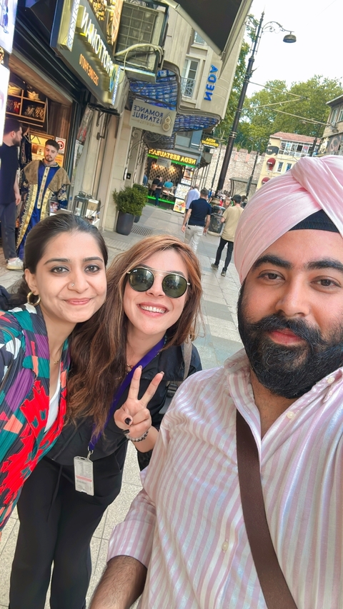 Three people smiling for a selfie in an urban setting.