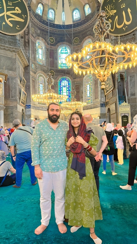 Couple inside a historical building with chandeliers and stained glass.