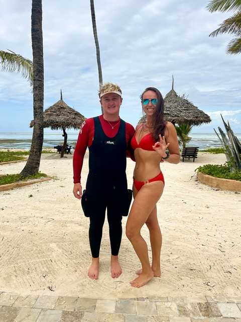 Couple posing on the beach in bright swimwear.