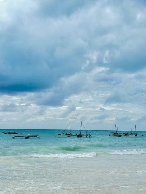 Seascape with traditional wooden boats and cloudy sky.