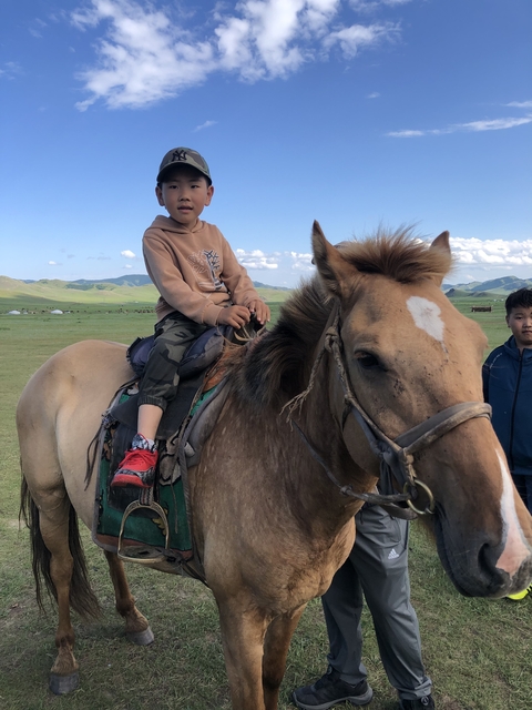       Child sitting on a horse with a plains landscape.
  