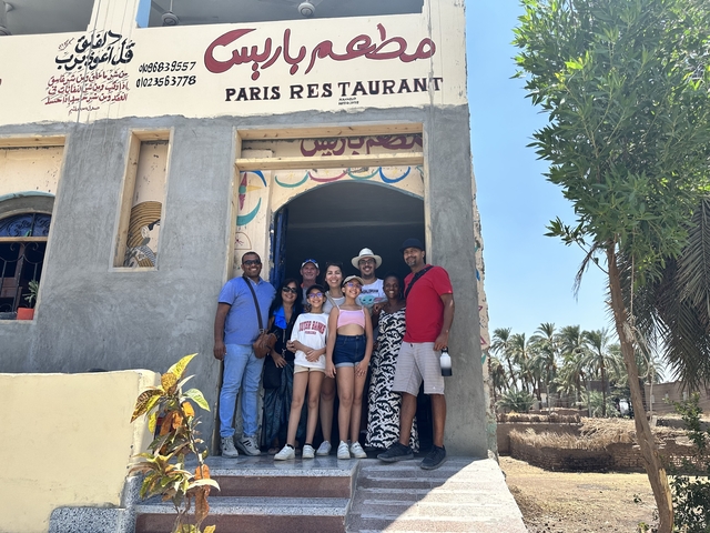       Group of people posing in front of a restaurant.
  