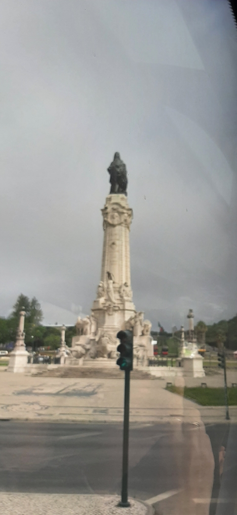 Blurry image of a monument or pillar in an urban area.