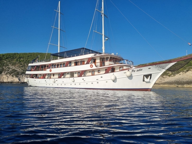 Large white yacht docked in a clear blue sea.