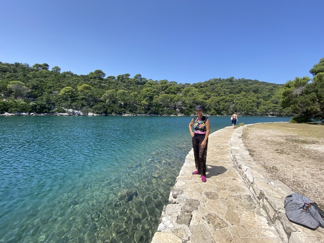 Person standing by the edge of a lake with a mountainous background.
