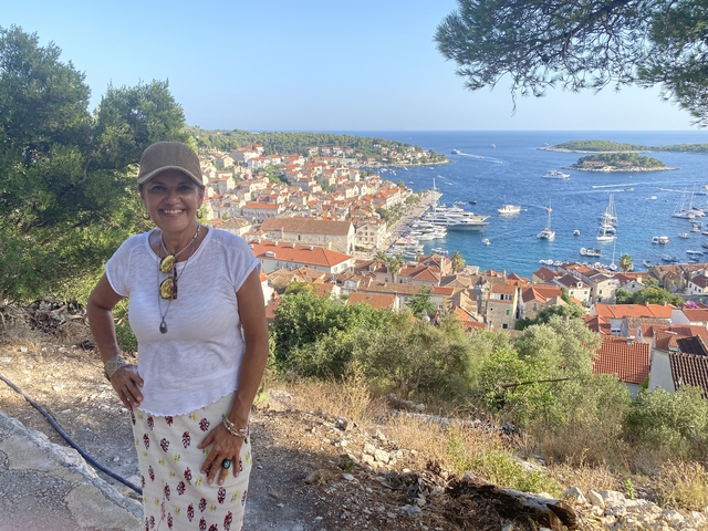 Woman posing in front of a coastal town with yachts.