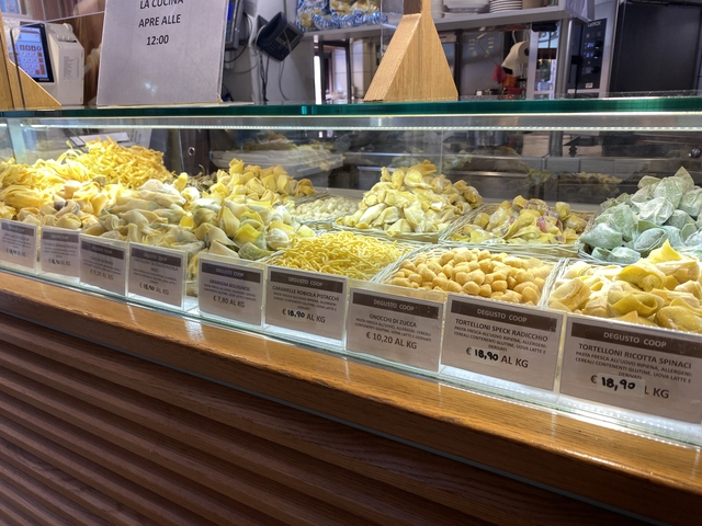 Display case with various types of pasta and prices.