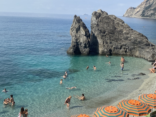 People swimming in turquoise water near rocky shores.