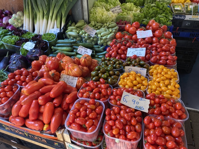       Colorful tomatoes and vegetables on display at a market.
  
