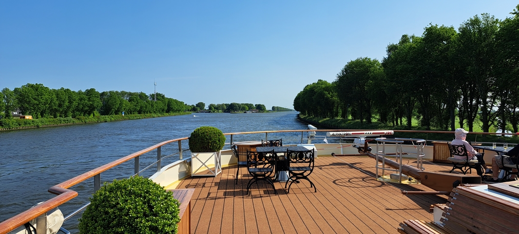 View from a boat on a river with lined trees and clear sky.