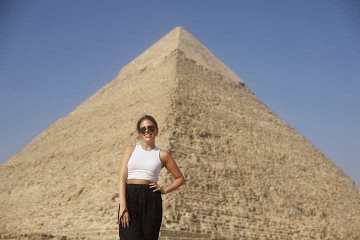 Person posing in front of a large pyramid.
