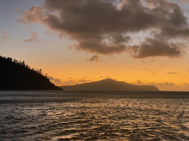 Silhouette of an island against an orange sunset sky.