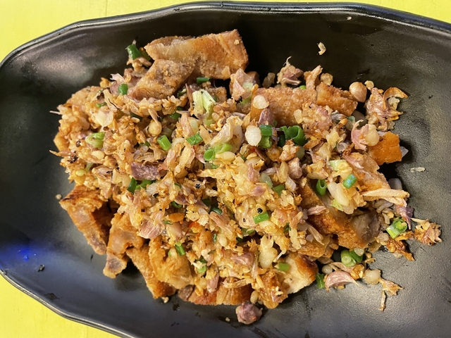 Dish with crispy cooked meat and garnished with green onions.