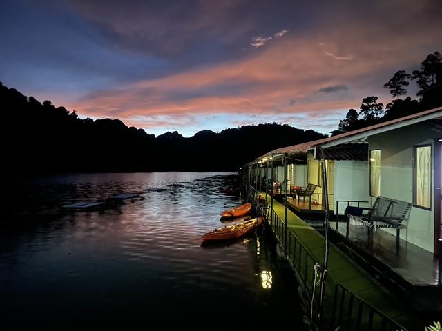 Floating accommodation with kayaks on a calm lake at dusk.